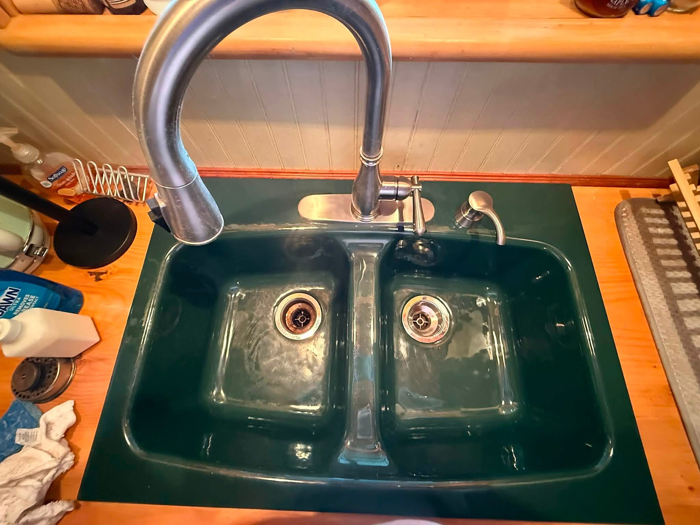 Before: dark green double kitchen sink in a cabin, hazy with hard water spots